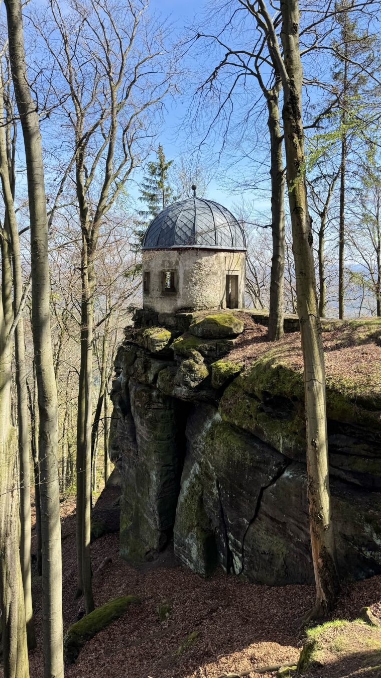 Ein alter steinerner Pavillon auf einem Felsvorsprung mitten im Wald